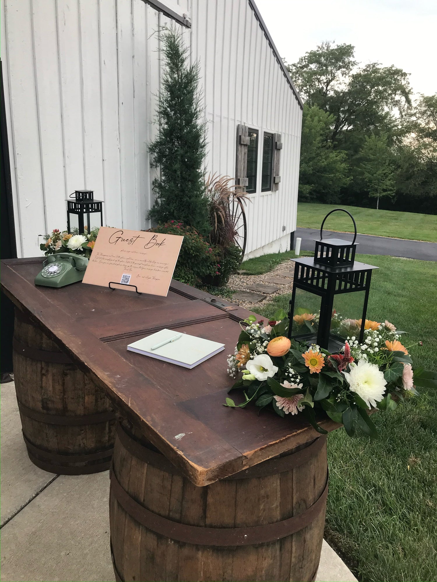 Decorative setup with flowers and a sign on a wooden barrel outdoors.